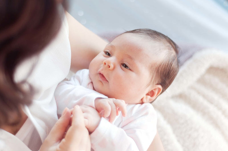 small new born baby looking at thier mums face