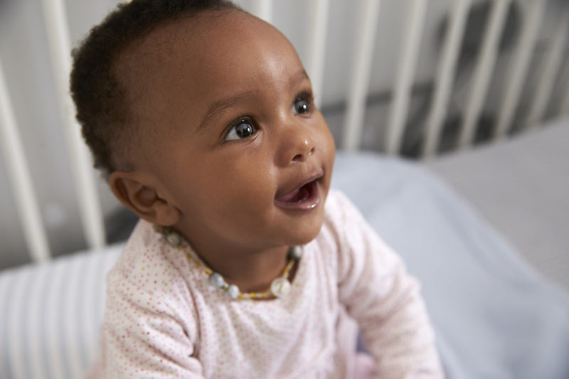 young baby with big briwn eyes inside a crib