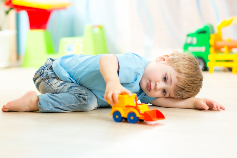 toddler with jeans and a blue t shirt playing with toy digger